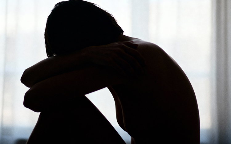 Person in protective posture reflecting on emotional patterns and defensive responses