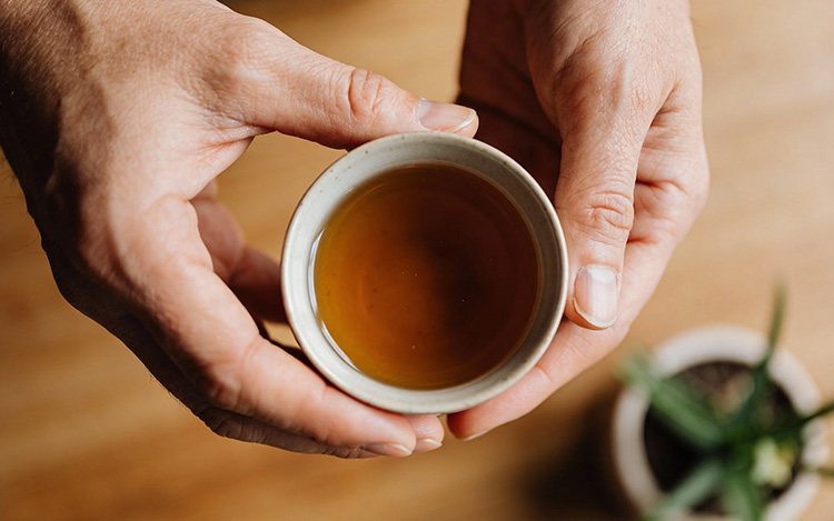 Hands holding warm beverage in peaceful moment, symbolising taking time for self-reflection and personal growth